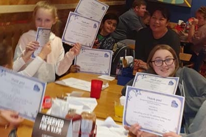 Foster squad children holding up their certificates around a table